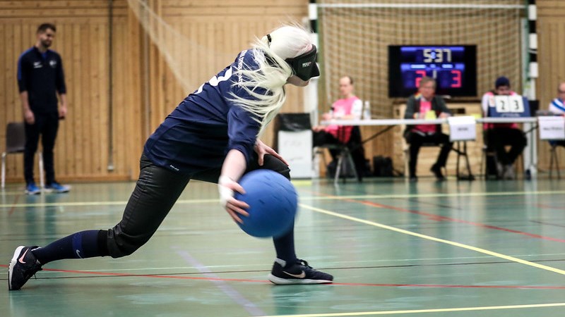 En kvinnlig goalballspelare kastar bollen i full fart.