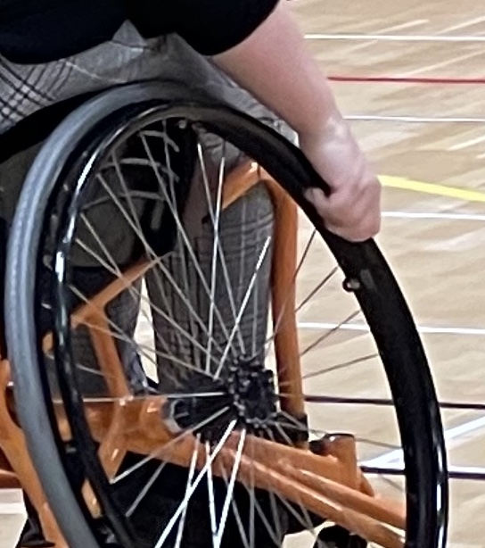 Bilden visar en person som greppar hjulet på en rullstol. 