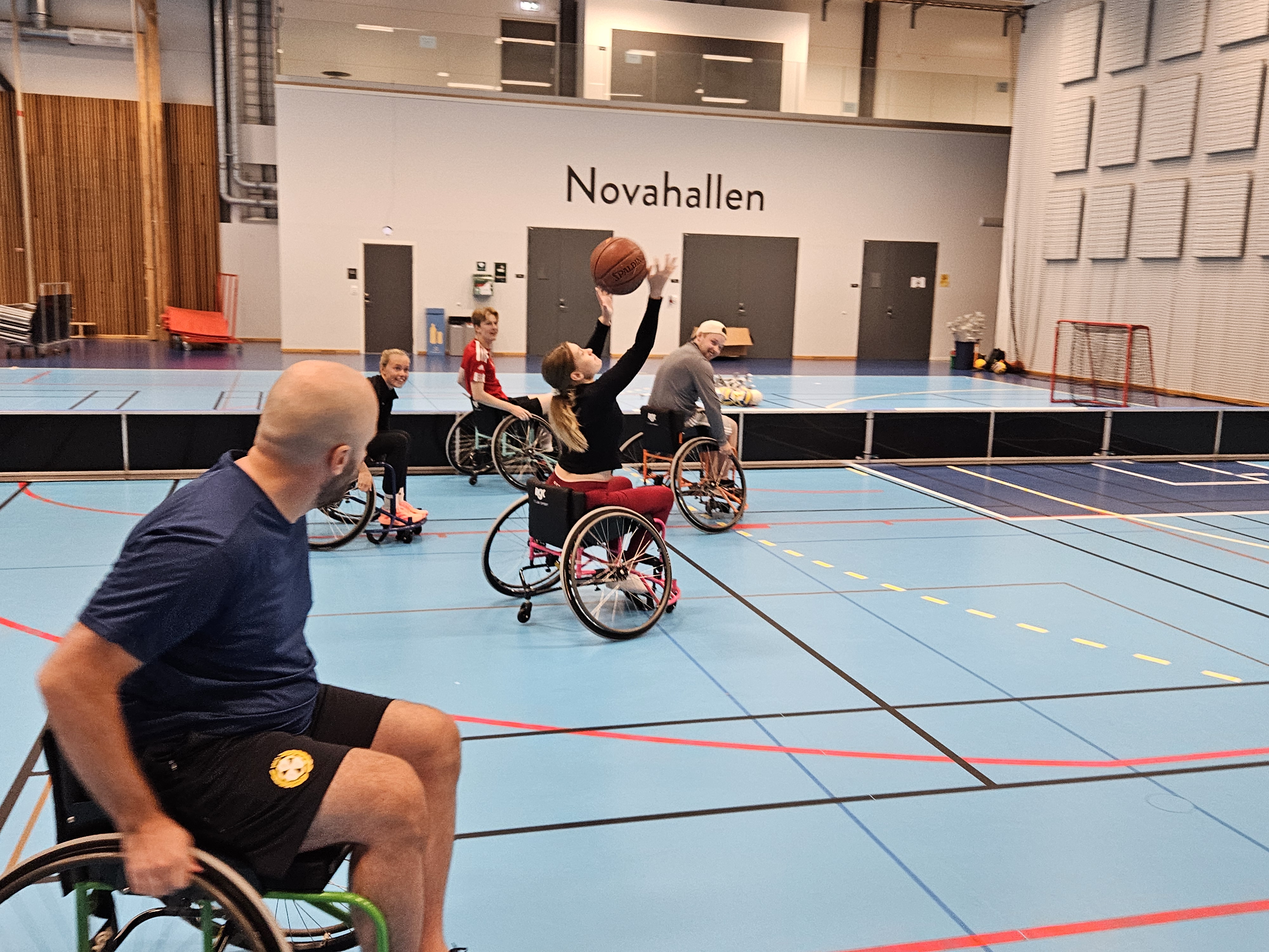 Studenter provar på rullstolsbasket i en idrottshall under en aktivitetsdag.