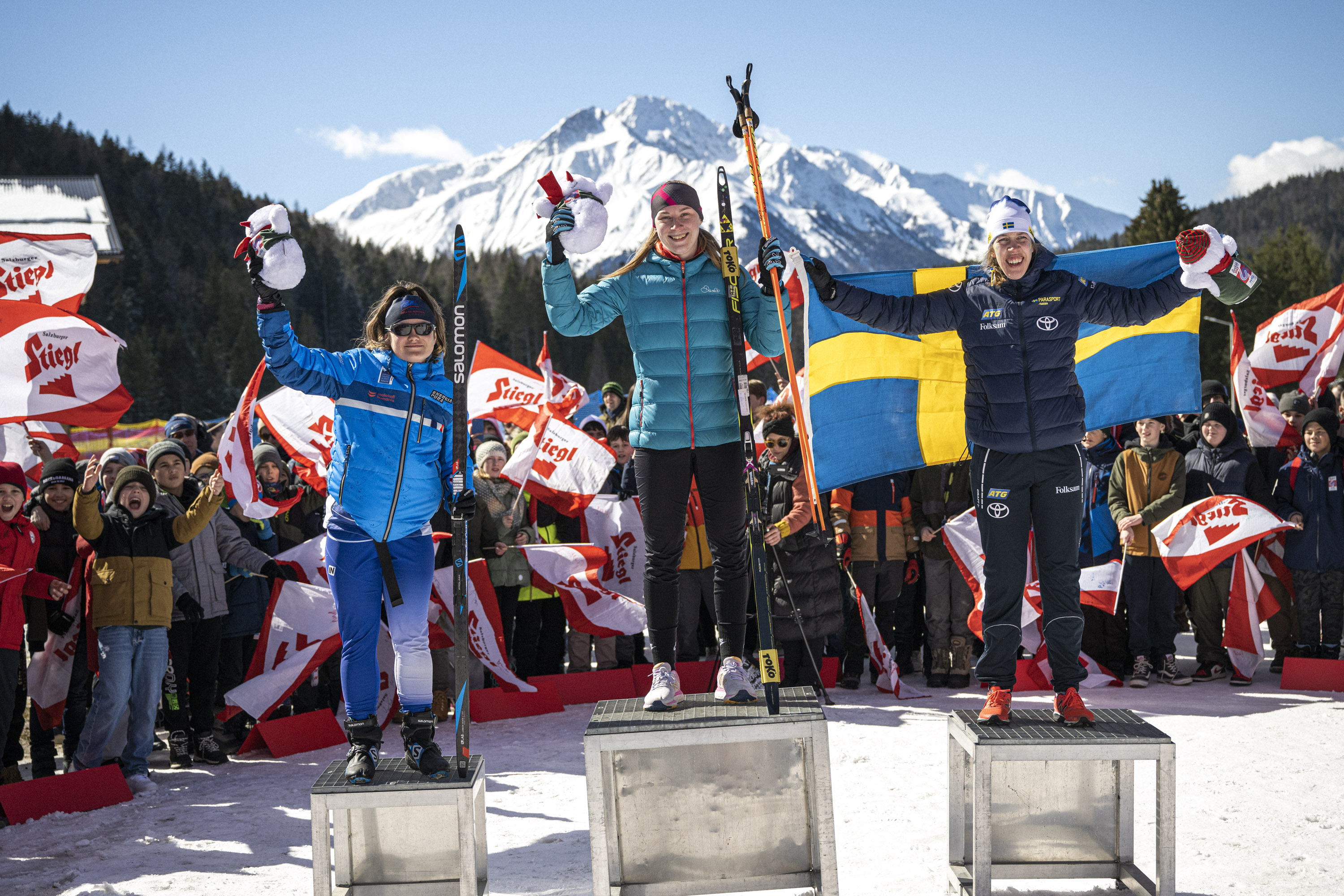 Kristin Björfeldt står på prispallen och håller upp den svenska flaggan bakom sig.